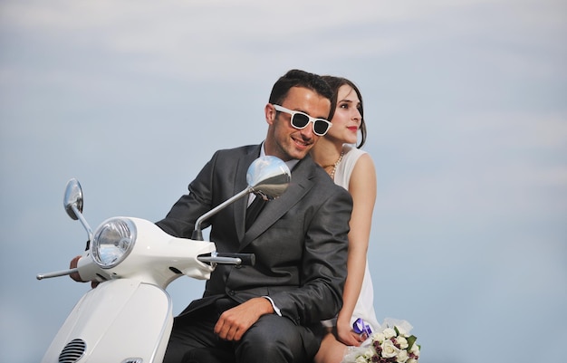 wedding sce of bride and groom just married couple on the beach ride white scooter and have fun