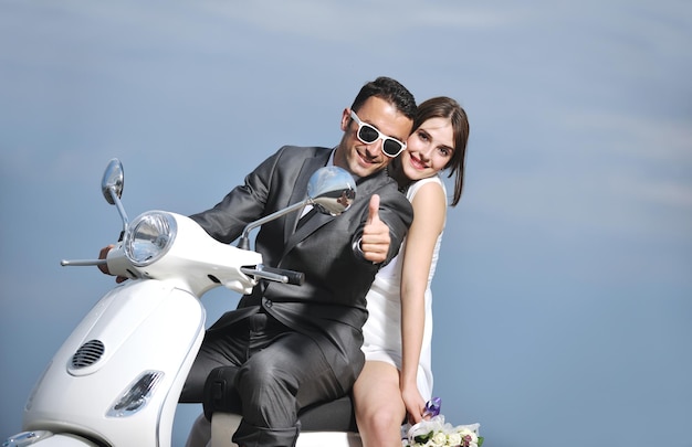 Scena del matrimonio degli sposi appena sposati sulla spiaggia, giro in scooter bianco e divertirsi