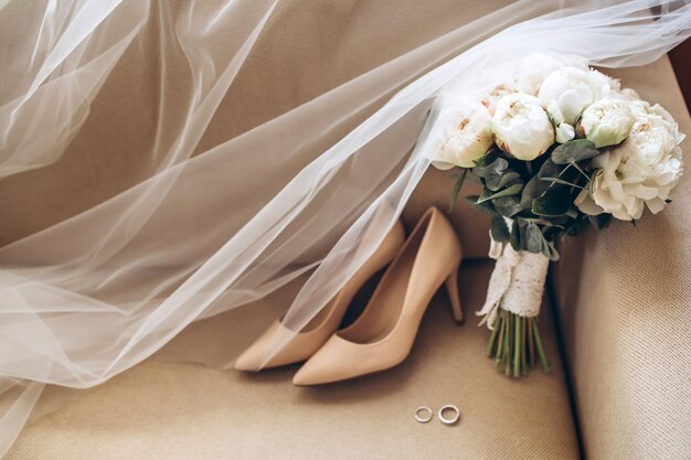 Wedding shoes of the bride with a bouquet of peonies and other flowers.