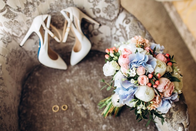 Wedding shoes of the bride with a bouquet of peonies and other flowers.