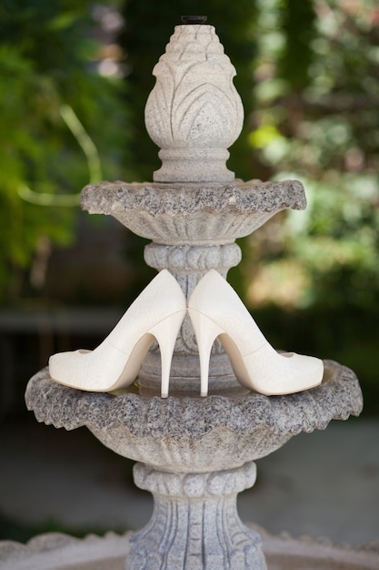 Wedding shoes on a green nature. Fountain.