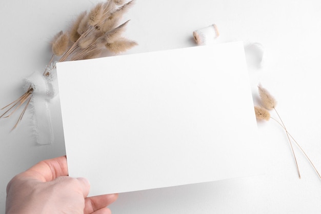 Фото Свадебный канцелярский макет пригласительного билета x на белом фоне с бохо декором женская рука держится