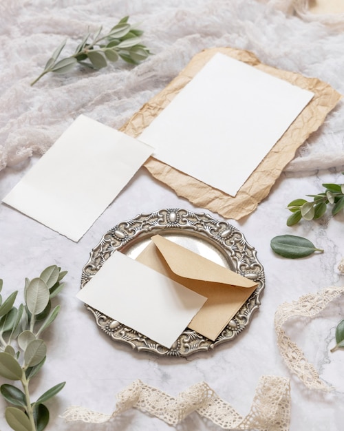 Foto cancelleria per matrimoni su un tavolo di marmo con rami di eucalipto e scena di mockup di nastri