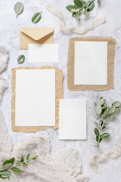 Wedding stationery set with envelope laying on a marble table decorated with eucalyptus branches