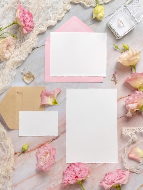 Wedding stationery set with envelope laying on a marble table decorated with flowers and ribbons