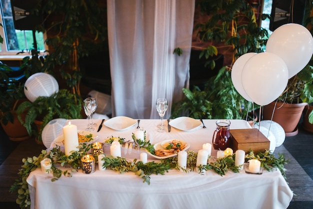 Photo wedding table of the bride and groom with white balloons and candles