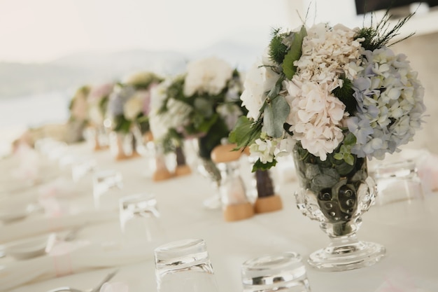 Wedding table decor in fresh air on background of sea. Floral table decorations for holidays and dinner. Serving for holiday, event, party or reception in an outdoor restaurant. Banner for site