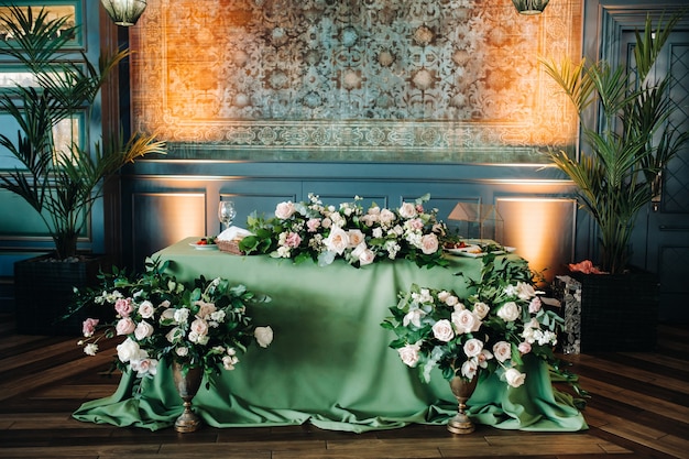 城のテーブルに花が飾られた結婚式のテーブルデコレーション、キャンドルライトによるディナーのテーブルデコレーション。