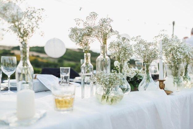 Wedding table set up in boho style with flowers and candle near to vineyard.