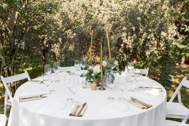 Wedding table setting decorated with fresh flowers in a brass vase. 