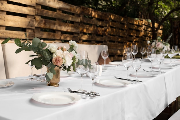 Wedding table setting decorated with fresh flowers in a brass vase. 