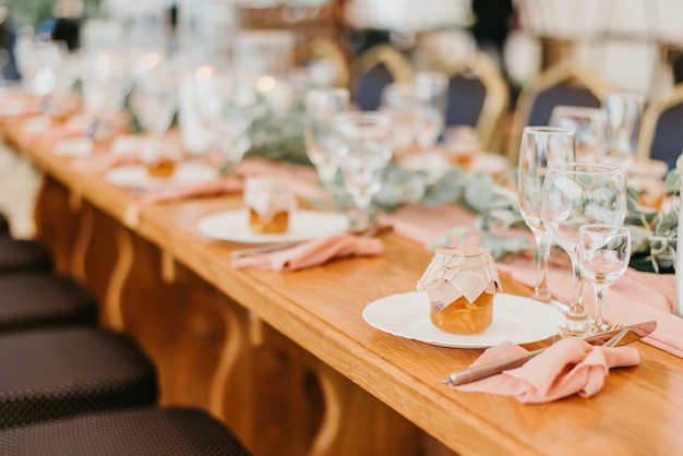 Сервировка свадебного стола в ресторане, украшенном цветами и свечами