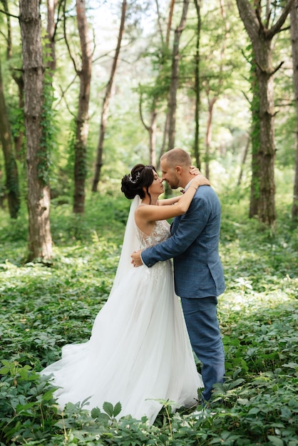 Свадебная прогулка жениха и невесты в лиственном лесу летом
