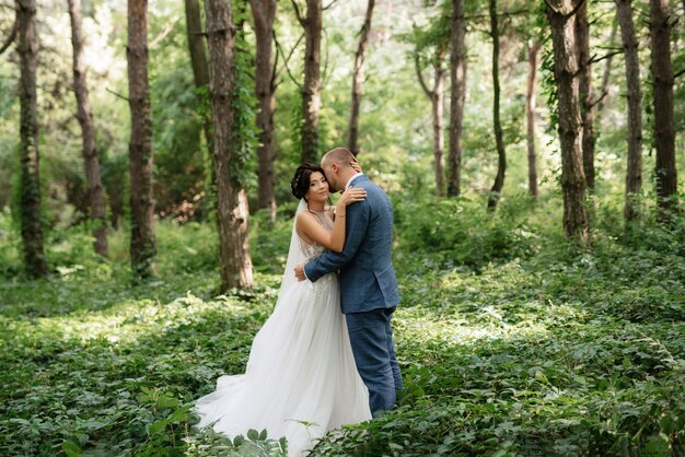 Wedding walk of the bride and groom in the deciduous forest in summer