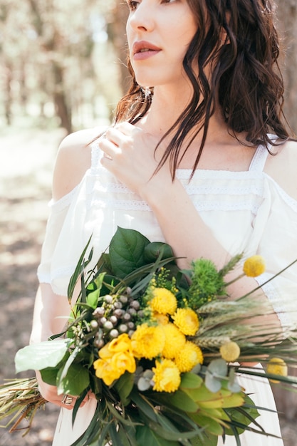 Wedding walk in the pine forest. Sunny day. Wedding couple in the forest. Beautiful Bride and groom on a walk. White wedding dress. Bouquet of peonies and hydrangeas.