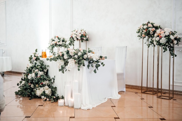 Wedding white banquet hall decorated with fresh flowers and a golden tablecloth