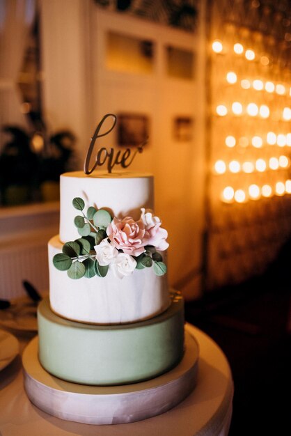 Photo wedding white cake on a high stand near the white podium