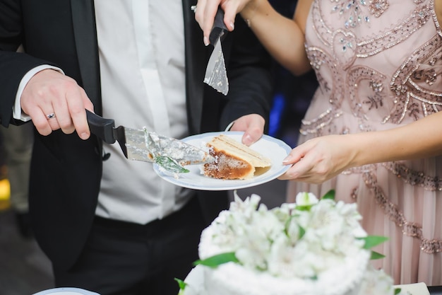 Фото Свадебный торт с белыми фруктами жених и невеста разрезают украшенный цветами свадебный торт