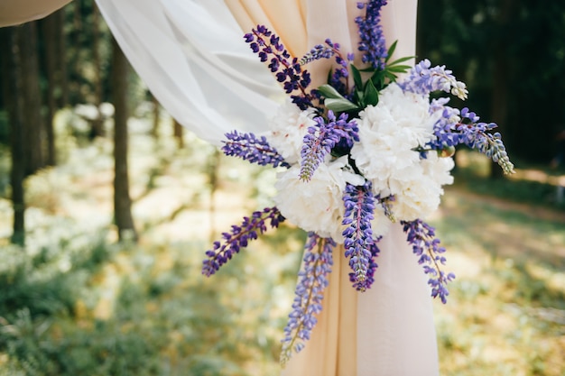 Wedding wooden arch for marriage ceremony decorated with blue field flowers.