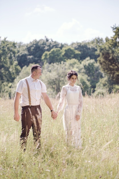 ヴィンテージスタイルの若い美しいカップルの結婚式。公園を散歩する新婚夫婦