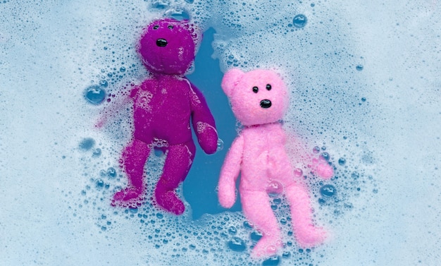 Foto week de speelgoedteddybeer voor het wassen in het water van wasmiddel.