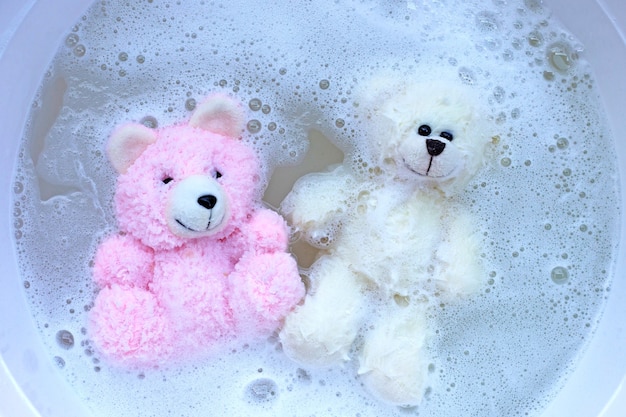 Week speelgoedberen in het oplossen van wasmiddel in water voordat ze worden gewassen. Wasserij concept, bovenaanzicht