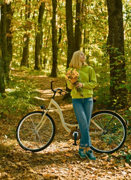 Weekend activity Active leisure and lifestyle Girl ride bicycle for fun Blonde enjoy relax forest Autumn bouquet Warm autumn Girl with bicycle and flowers Woman with bicycle autumn forest