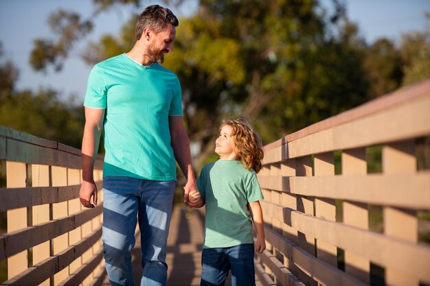 Weekend activity happy family lifestyle concept Happy father and little boy son walking in summer park Father parenting his son