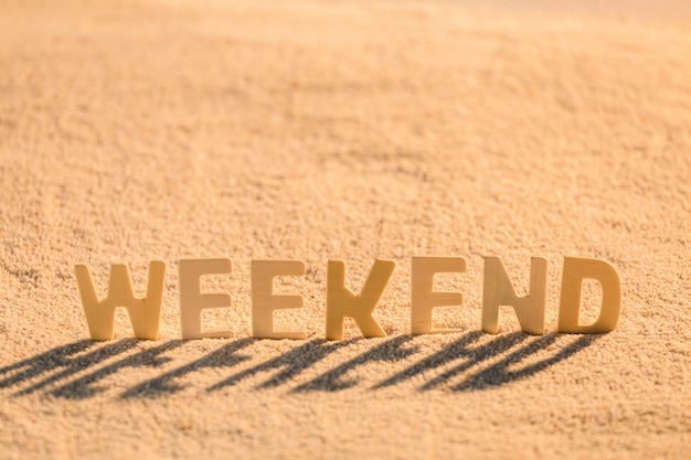 写真 週末-砂のビーチに置かれた木製アルファベットのビジネスモチベーションのコンセプト