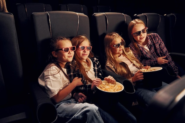 Weekend fun Group of kids sitting in cinema and watching movie together