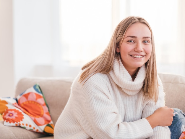 Weekend pastime. casual cosy clothing. young smiling happy girl sitting on sofa in the comfort of her home