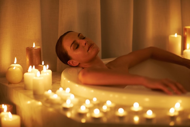 몇 주 동안의 걱정이 씻겨 나갔다. 촛불이 켜진 목욕에서 휴식을 취하는 멋진 여성의 자른 샷