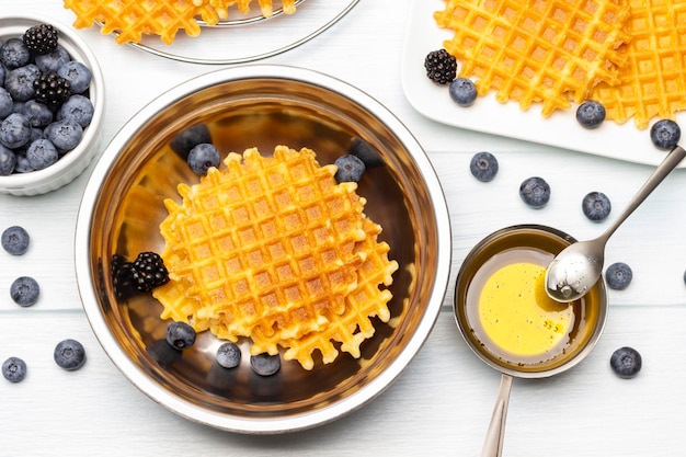 Weense wafels en bessen in een metalen kom Honing in een kom Bosbessen op tafel