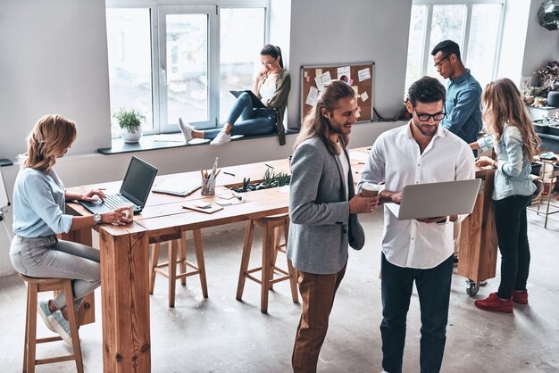 Foto weer een werkdag. groep moderne jonge mensen die samenwerken terwijl ze tijd op kantoor doorbrengen