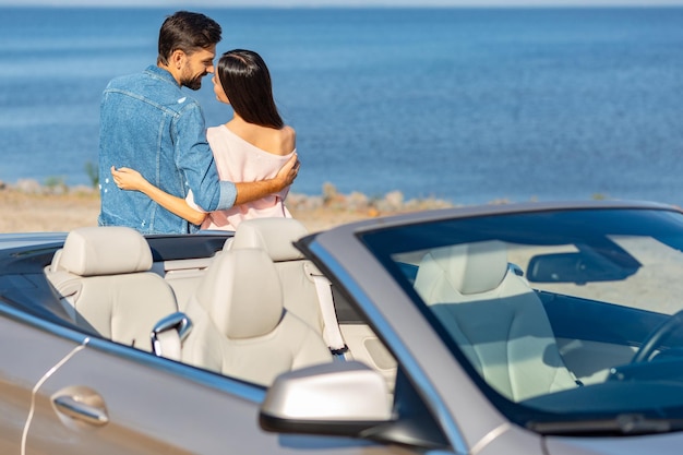 Weergave van cabriolet met jong stel dat elkaar omhelst op de achtergrond