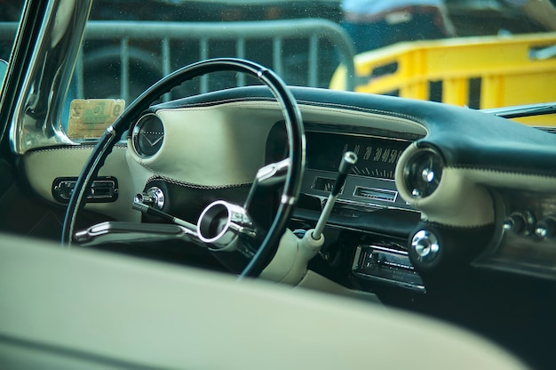 Foto weergave van dashboard, stuurwiel, indicatoren en timing meters van een vintage amerikaanse auto met alle details van het interieur zichtbaar.