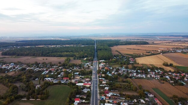 Weergave van een dorp en snelweg in Roemenië, lage woongebouwen, bos, velden, uitzicht vanaf de drone, Roemenië