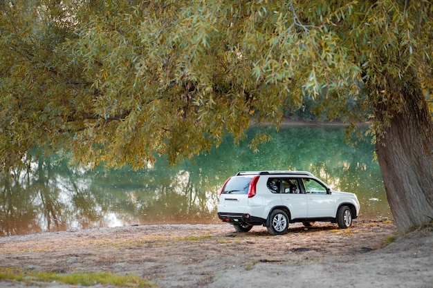 Weergave van suv-auto op het strand van de rivier bij zonsondergang. kopieer ruimte