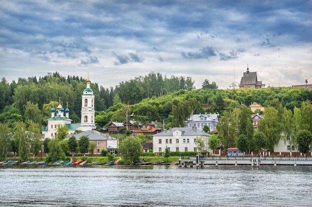 Weergave van woongebouwen aan de kade, de Varvara-kerk en de kerk van Peter en Paul op de berg Levitan in de stad Plyos (Ivanovo-regio) vanaf de Wolga op een bewolkte zomerdag