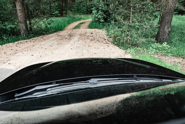 Weergave van zwarte auto kap op bosweg achtergrond.