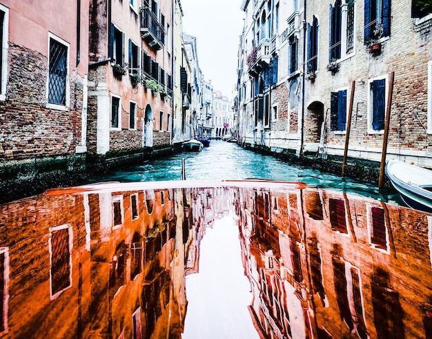 Weerspiegeling van de huizen op het gelakte houten kapponton van de watertaxi in de straten van Venetië die vertrekt