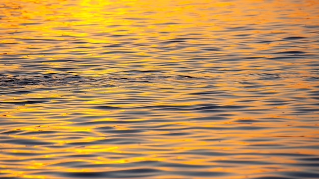 Weerspiegeling van de ondergaande zon in een golf van water. Natuurlijke achtergrondstructuur