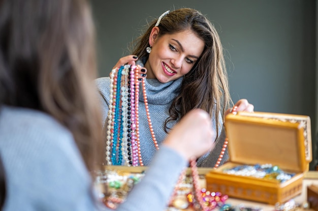 Weerspiegeling van een vrouw in de spiegel die verschillende sieraden soft focus close-up kiest en probeert