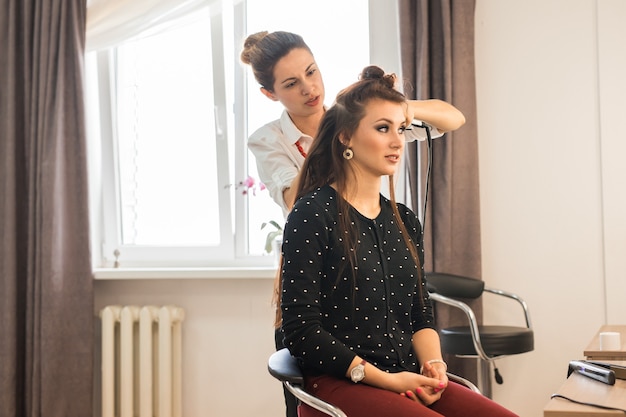 Weerspiegeling van kapper die kapsel voor vrouw in kapper doet. concept van mode en schoonheid