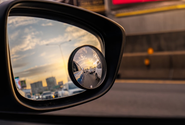 Weerspiegeling van verkeersstroom op asfaltweg in zijspiegel van blauwe SUV. Autovleugelspiegel met bolle spiegel voor veilig rijden.