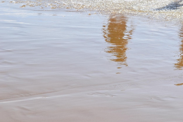 Weerspiegeling van voeten op het zand aan zee zonnige schaduw van voeten op nat zand