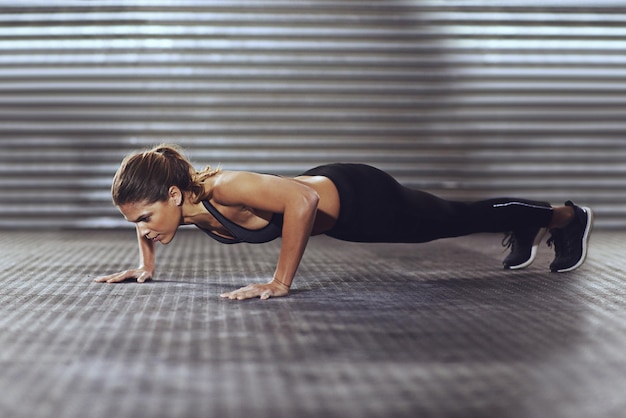 Foto wees je eigen beste motivatie shot van een jonge vrouw die push-ups doet in de sportschool