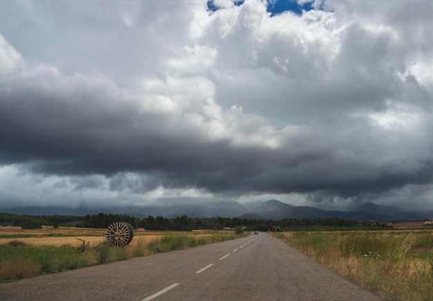 Weg bos bergen en velden in Grieks dorp in een zomerstorm met zwarte wolken in Griekenland