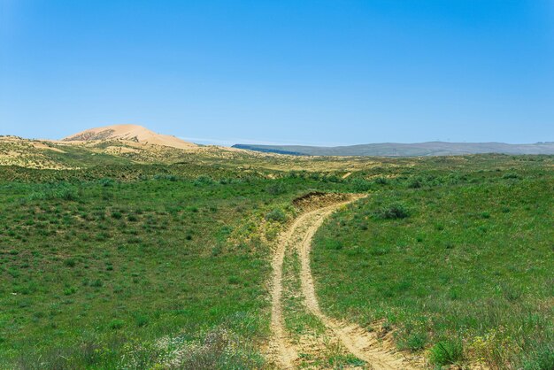 Weg in halfwoestijn steppelandschap in de buurt van de zandduin van Sarykum