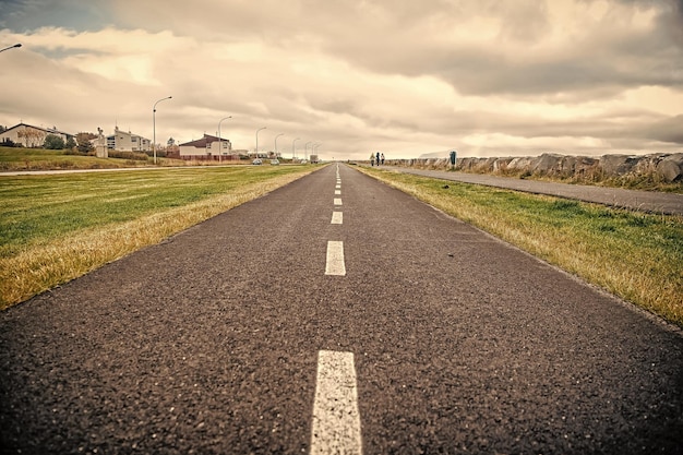 Weg op bewolkte hemel in reykjavik, ijsland Asfaltweg met oppervlaktemarkering met gras aan de zijkanten Reizen en reislust Vrijheidsconcept of perspectief en toekomst